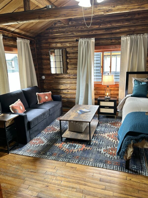 A room in the Alpine Standard Cabin #2 with a bed, couch and coffee table.