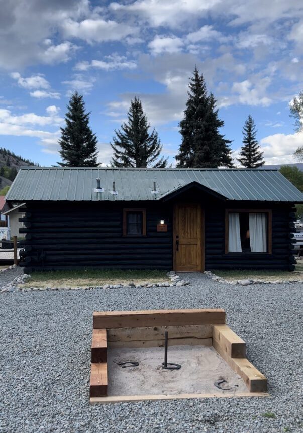 An Alpine Standard Cabin #3 with a fire pit in front of it.